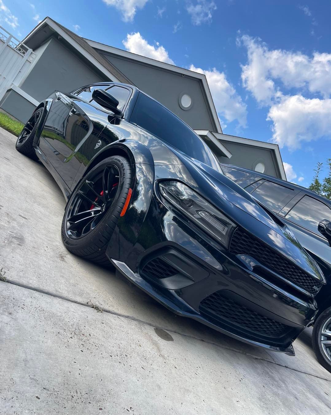 Freshly detailed black Dodge Charger widebody with glossy paint and clean wheels in a driveway