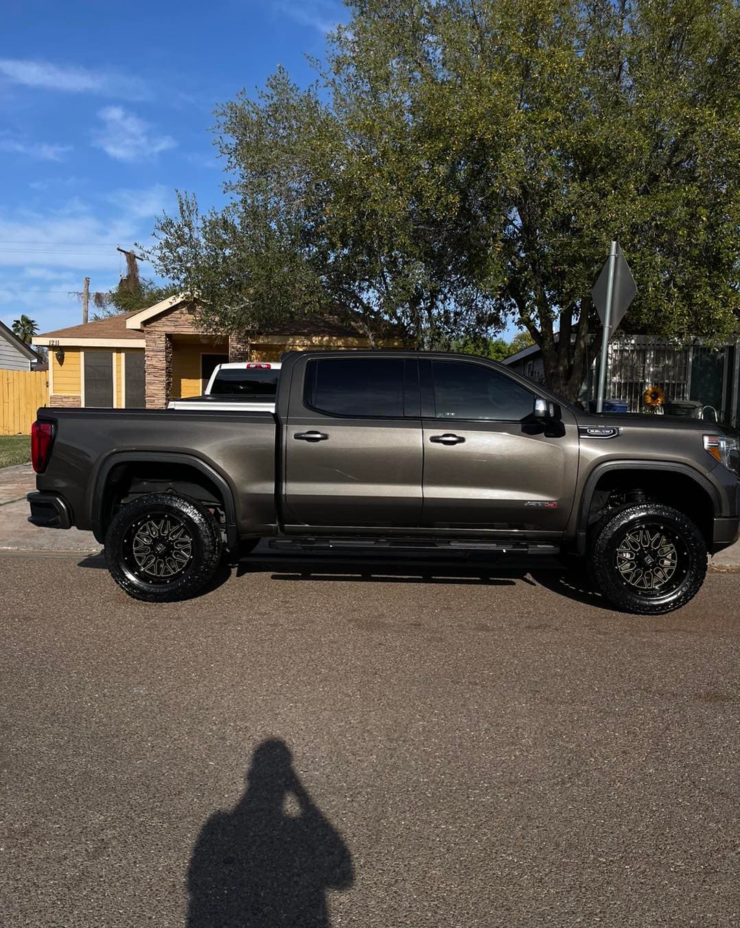 Lifted bronze GMC Sierra AT4 truck cleaned and detailed, side profile on a Laredo street